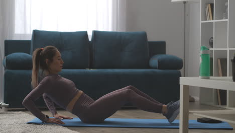 fitness-model-is-doing-crunches-for-slim-abdomen-at-home-sitting-on-floor-and-lifting-torso-and-legs-active-sporty-woman-physical-exercise-for-body-shaping